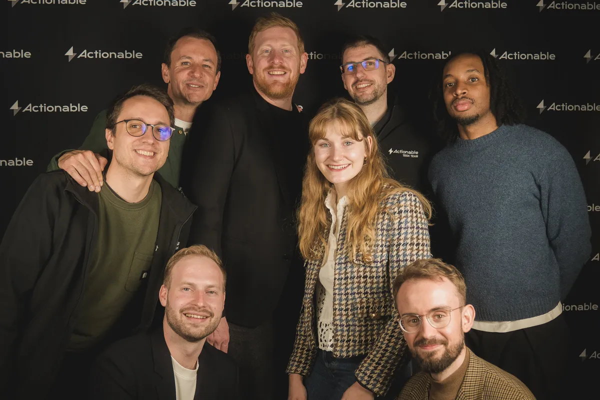 Actionable team photo, everyone posing together in front of the Actionable photo wall